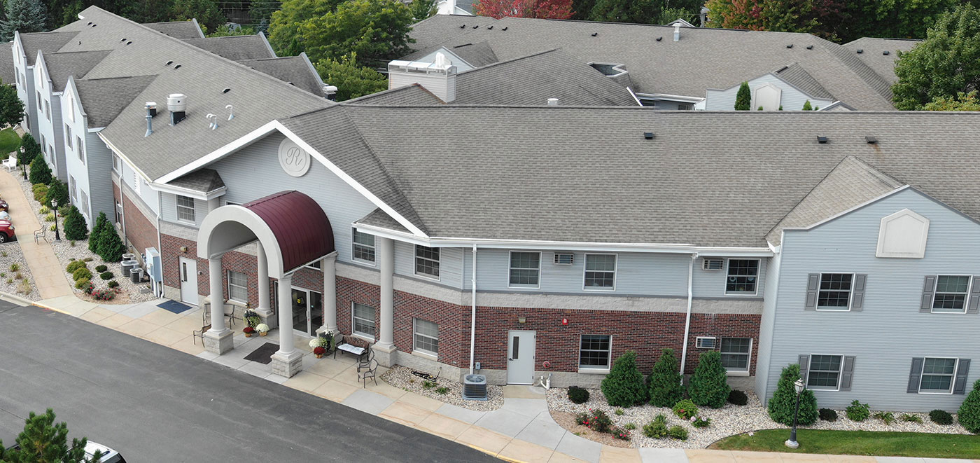 Exterior view of Renaissance Assisted Living in Appleton, WI — brick and siding building with covered entrance, surrounded by landscaping.